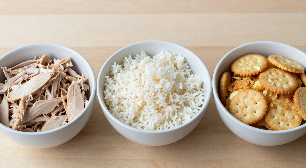shredded chicken, cooked white rice and crushed buttery crackers in three white prep bowls
